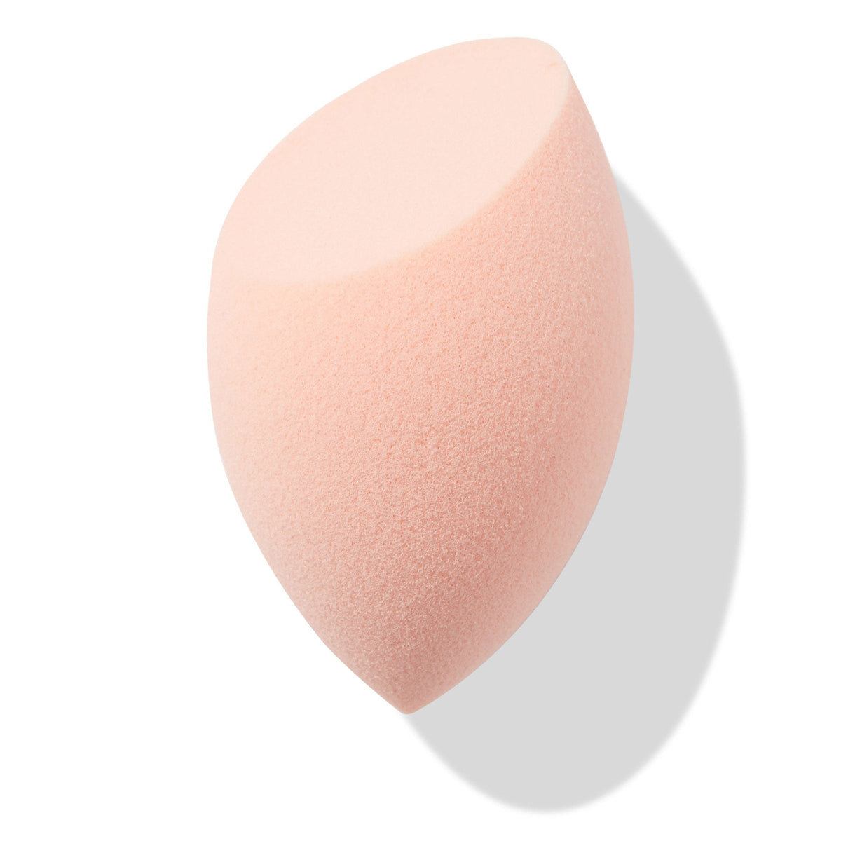 Peach teardrop Blending Sponge with a flat slanted edge resting at an angle, showing fine foam texture for seamless foundation and concealer blending, isolated on white with soft shadow; a must-have in ColourPop Makeup Tools & Accessories.