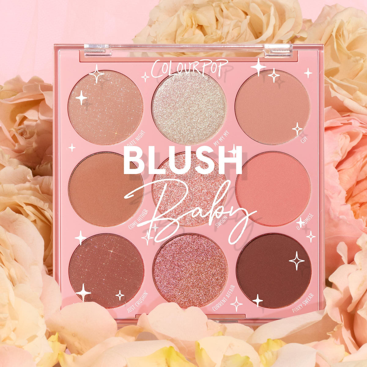 Blush Baby ColourPop Shadow Palette showcases nine pink and nude hues - matte, shimmer, and glitter - arranged in a pink compact, displayed open among soft cream and peach roses for a romantic spring makeup look.