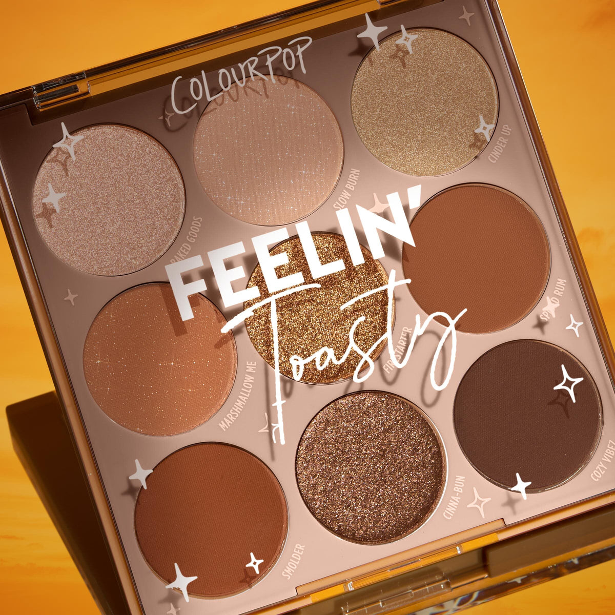 ColourPop Shadow Palette Feelin' Toasty shows a nine-pan warm neutral eyeshadow range - matte tans, rich browns, and glittering golds - in a square compact under a closed clear lid with star graphics, styled on a golden sunset backdrop.