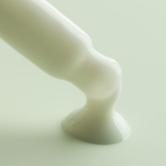 Matcha Face Milk flowing from an applicator tip and pooling into a glossy white puddle on a soft mint background, highlighting the creamy texture of ColourPop Face Milk skincare.