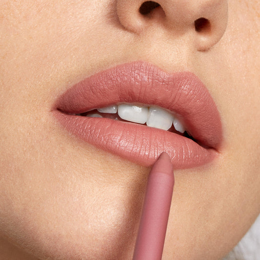 Oh Snap ColourPop Lippie Pencil lining lips in a soft dusty rose nude, tip pressed to the lower lip for precise definition in a close-up beauty shot, showcasing the creamy formula and smooth matte finish for sculpted, everyday lip color.