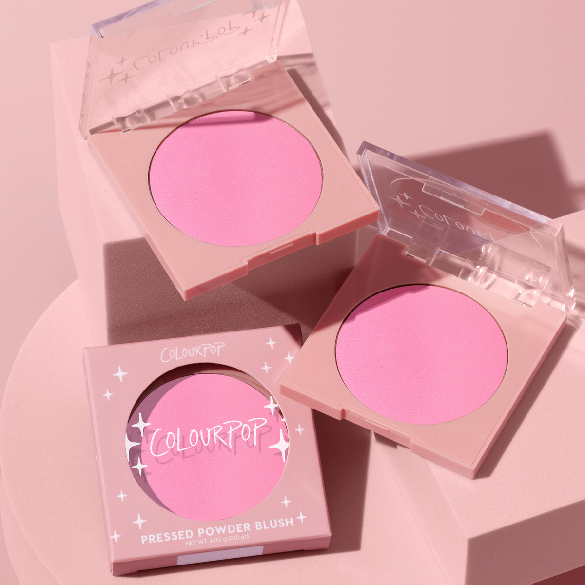 ColourPop Pressed Powder Blush Prairie Air displayed in three square compacts - two open showing a cool pink pan, one boxed with starry branding - arranged on pastel pink blocks under soft studio light, 6.0 g/0.21 oz.