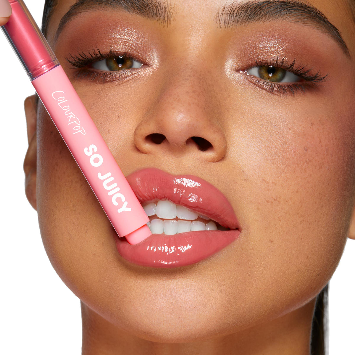 ColourPop So Juicy Plumping Gloss Balm with Peptides in Guava Glaze slicked onto full, glossy pink lips as the chubby pink tube is held to the mouth, close-up beauty shot with dewy skin and soft shimmer eye makeup.