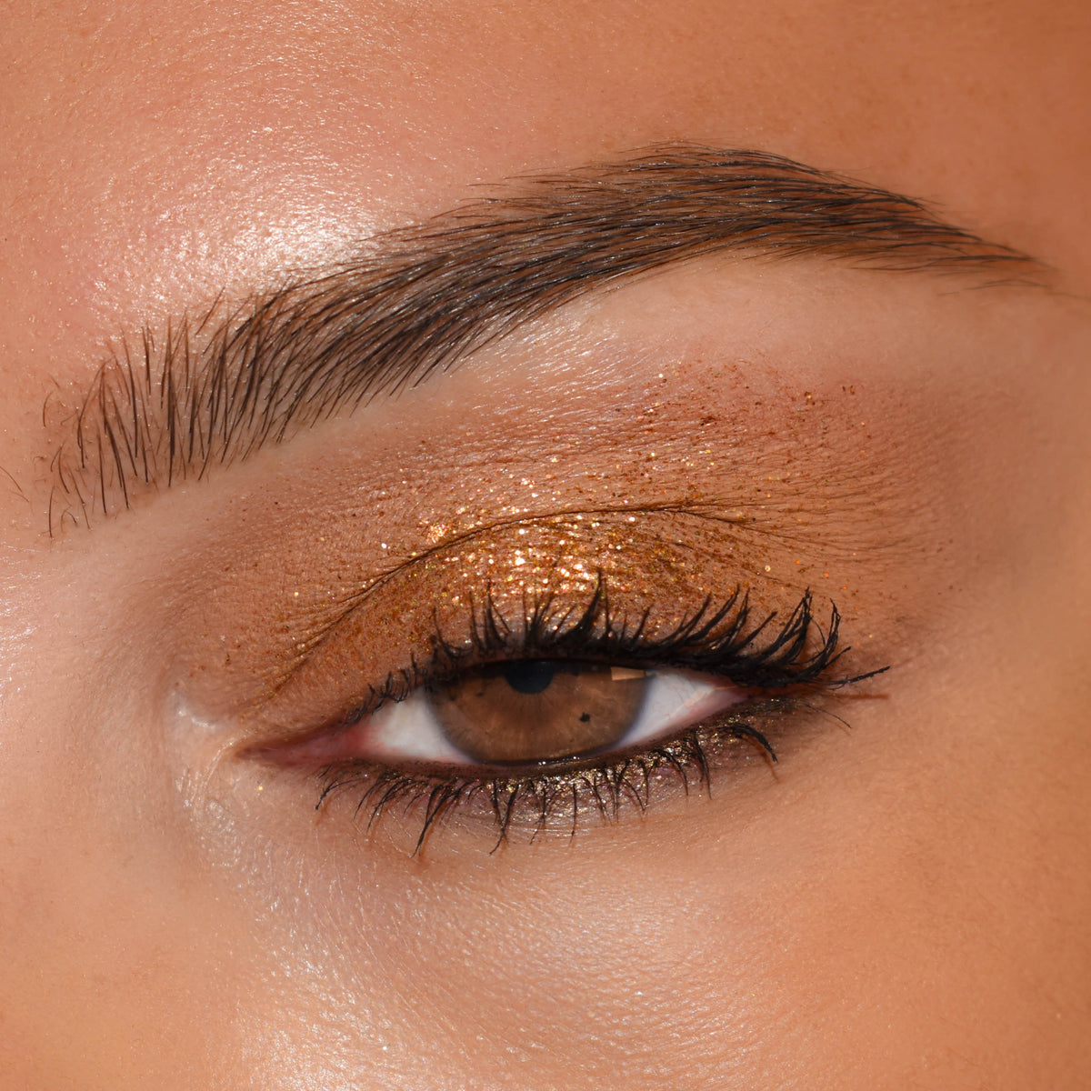 Brown eye wears shimmering copper-gold lids with defined lashes, showcasing the 11:11 ColourPop Shadow Palette shadow's rich bronze sparkle and smooth blend in a close-up beauty shot, perfect for soft neutral glam.