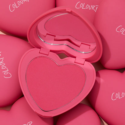 ColourPop Pressed Powder Blush Text Me opens to reveal a heart-shaped vivid pink pan with built-in mirror, set in a matte hot‑pink compact and surrounded by matching ColourPop heart cases, highlighting a romantic, travel-friendly cheek color.