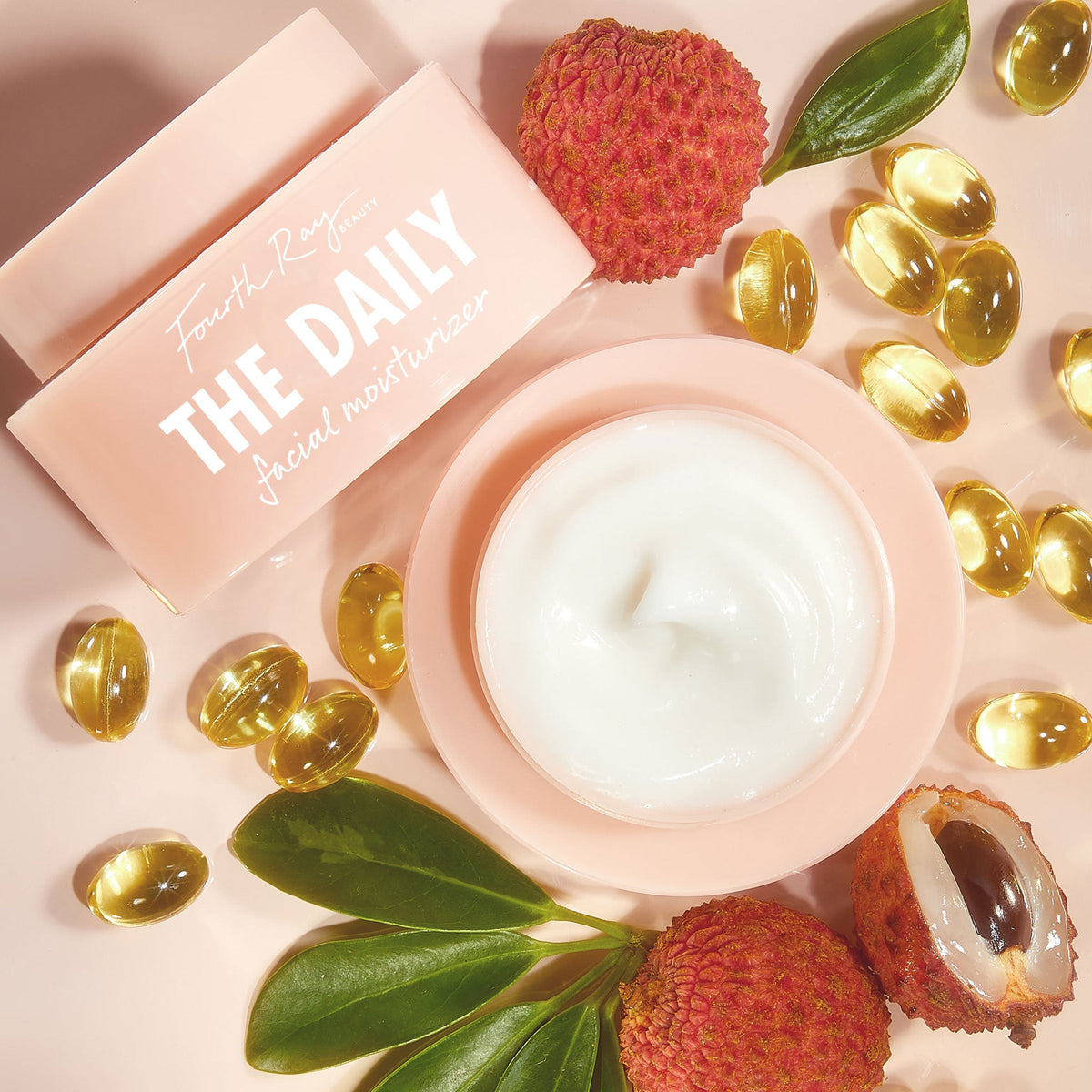 The Daily Face Cream shows a silky white swirl in a blush-pink tub beside its pastel box, lychee fruit with green leaves, and golden vitamin capsules, presenting a lightweight ColourPop Face Moisturizer for daily hydration.