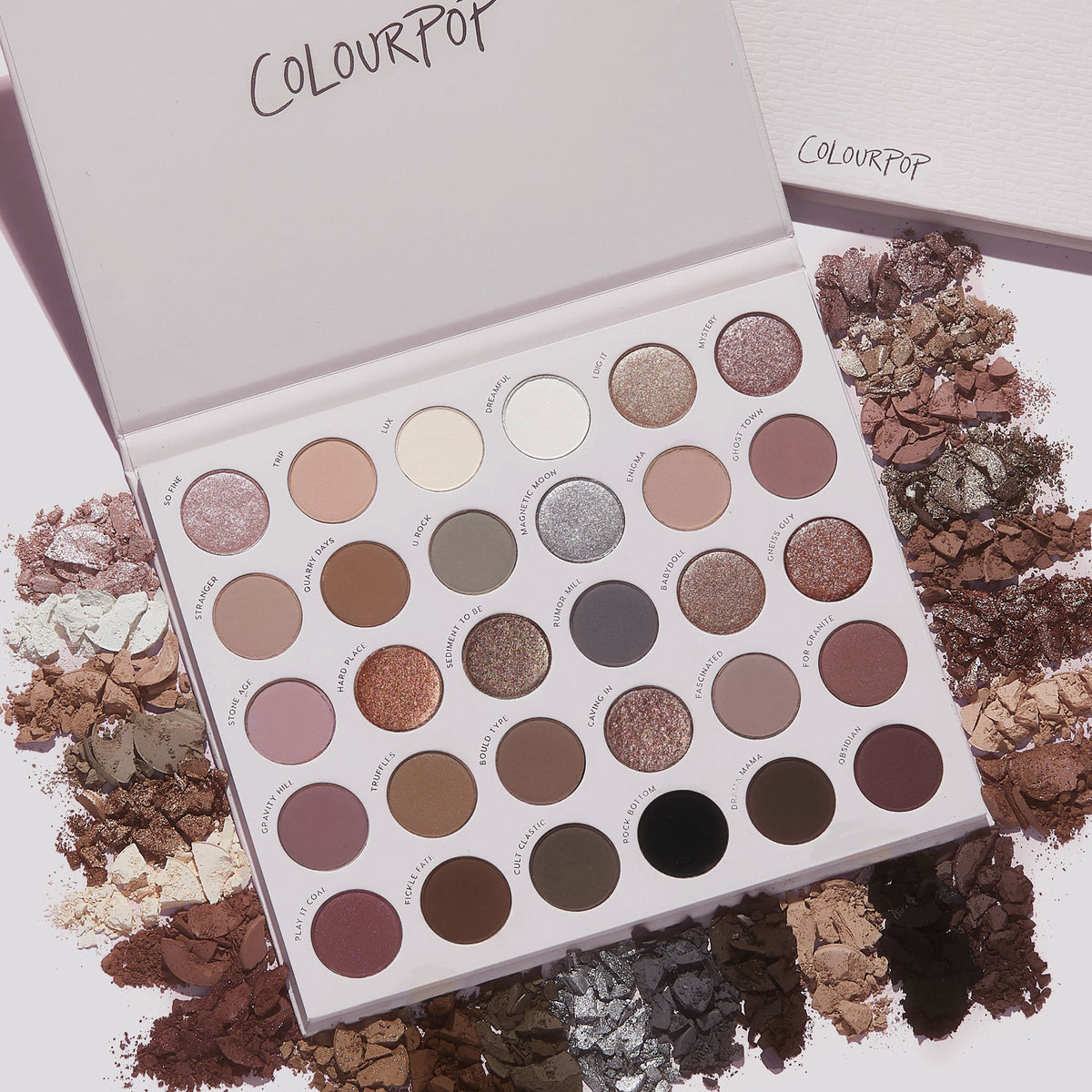 Stone Cold Fox ColourPop Shadow Palette lying open, displaying 30 cool‑toned neutral eyeshadows in matte and shimmer finishes; taupe, mauve, gray and champagne pans ringed by crushed powder swatches on a light backdrop.