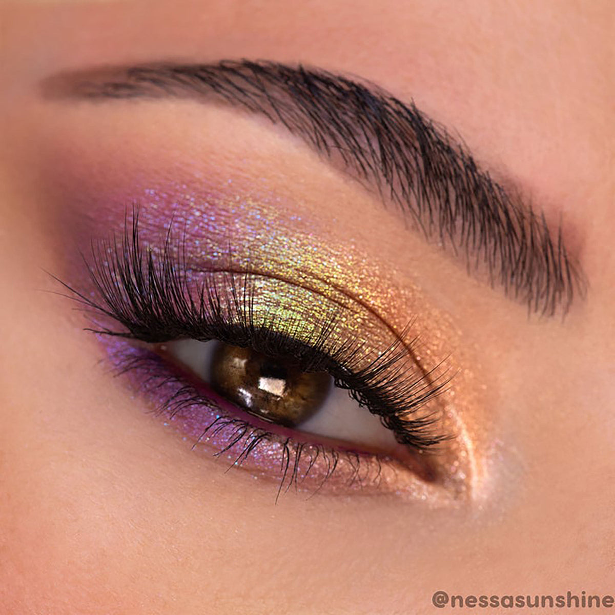 La Mesa ColourPop Super Shock Shadow glows across a partially closed eye, shifting gold, lime, and lavender as it catches light; blended on lid and lower lash line beneath long lashes, highlighting the metallic, duochrome payoff.