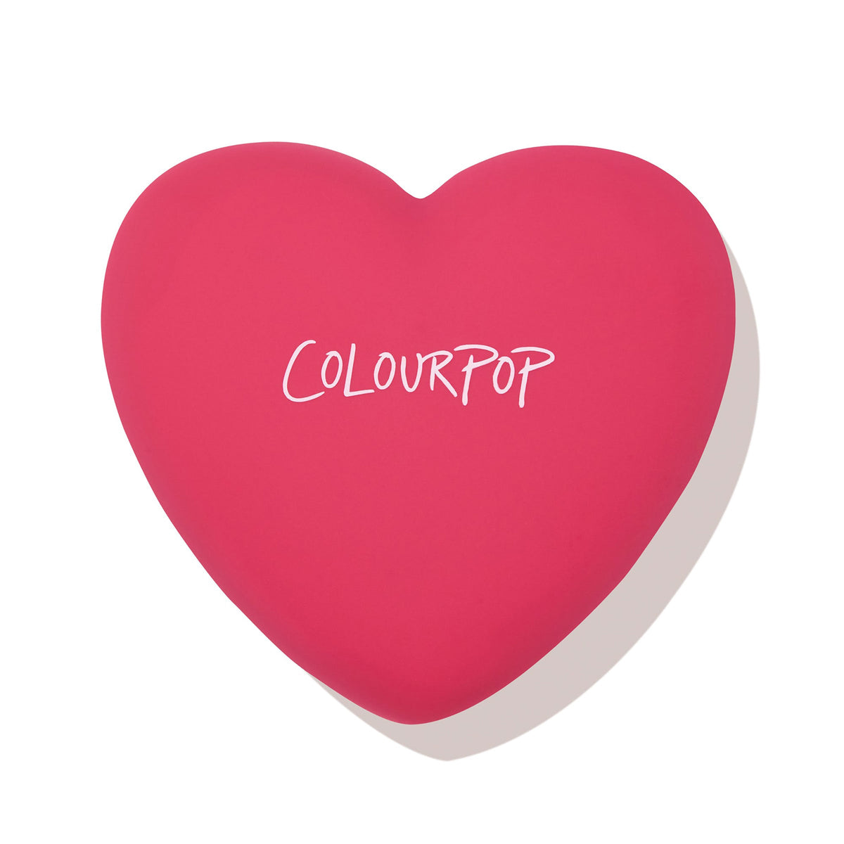 Heart-shaped hot pink compact with white ColourPop logo, closed and casting a soft shadow, featuring the Text Me shade of ColourPop Pressed Powder Blush; sleek travel-friendly pressed powder blush on a clean white background.