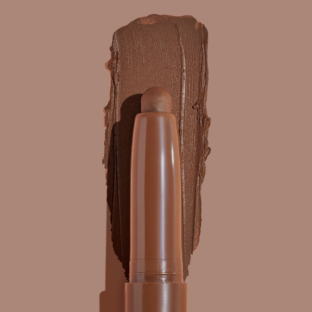 Walnut Ave ColourPop Shadow Stix sweeping a thick, matte walnut-brown swatch on a taupe background, showing the twist-up cream eyeshadow pencil tip and rich pigment payoff for easy, on-the-go eye color.