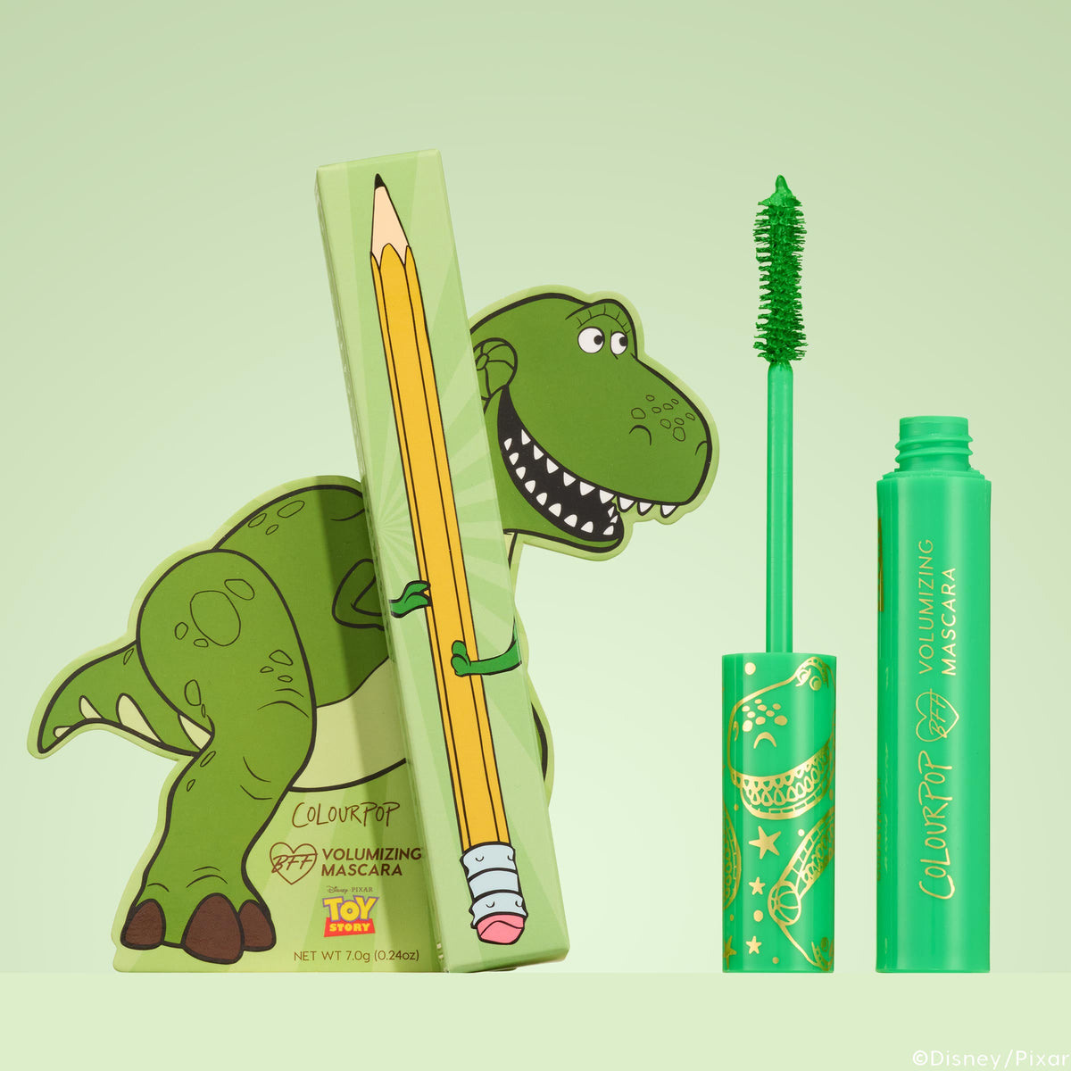 ColourPop BFF Mascara Roar! stands upright with a vivid green brush, shown beside Disney•Pixar Toy Story Rex–themed packaging and a pencil-print box; volumizing neon‑green tube set against a soft mint background.
