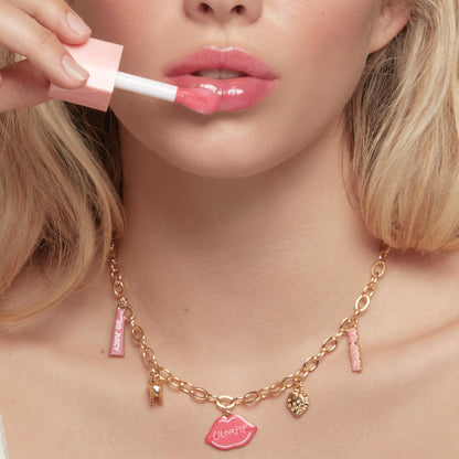 So Juicy lip oil glides onto glossy pink lips with a doe-foot applicator as a gold charm necklace - featuring a pink ColourPop lips pendant and mini So Juicy tube - rests on the neck; Charmed and Juicy, the ColourPop So Juicy Lip Oil and Necklace Set.