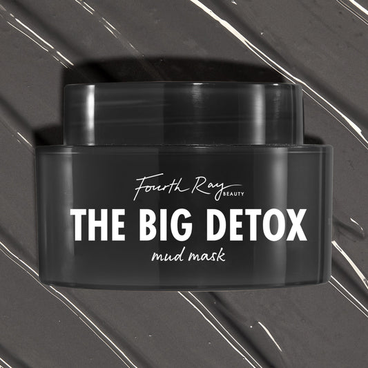 Black Fourth Ray Beauty The Big Detox Mud Mask jar displayed in a close-up flat lay, the ColourPop Face Mask resting on swirled charcoal mud with white streaks, showcasing the sleek container and bold white logo for detoxifying skincare.