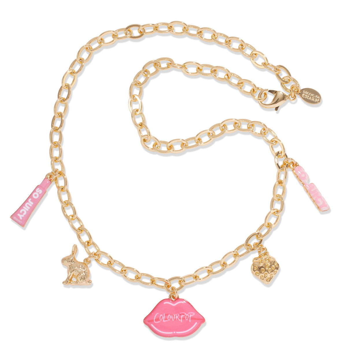 Gold charm necklace with oval links displays dangling pink ColourPop lips charm, mini “So Juicy” lip tube, bunny, strawberry, and pink enamel tag, laid on white; part of the Charmed and Juicy ColourPop So Juicy Lip Oil and Necklace Set.