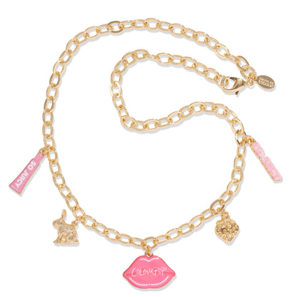 Gold charm necklace with oval links displays dangling pink ColourPop lips charm, mini “So Juicy” lip tube, bunny, strawberry, and pink enamel tag, laid on white; part of the Charmed and Juicy ColourPop So Juicy Lip Oil and Necklace Set.