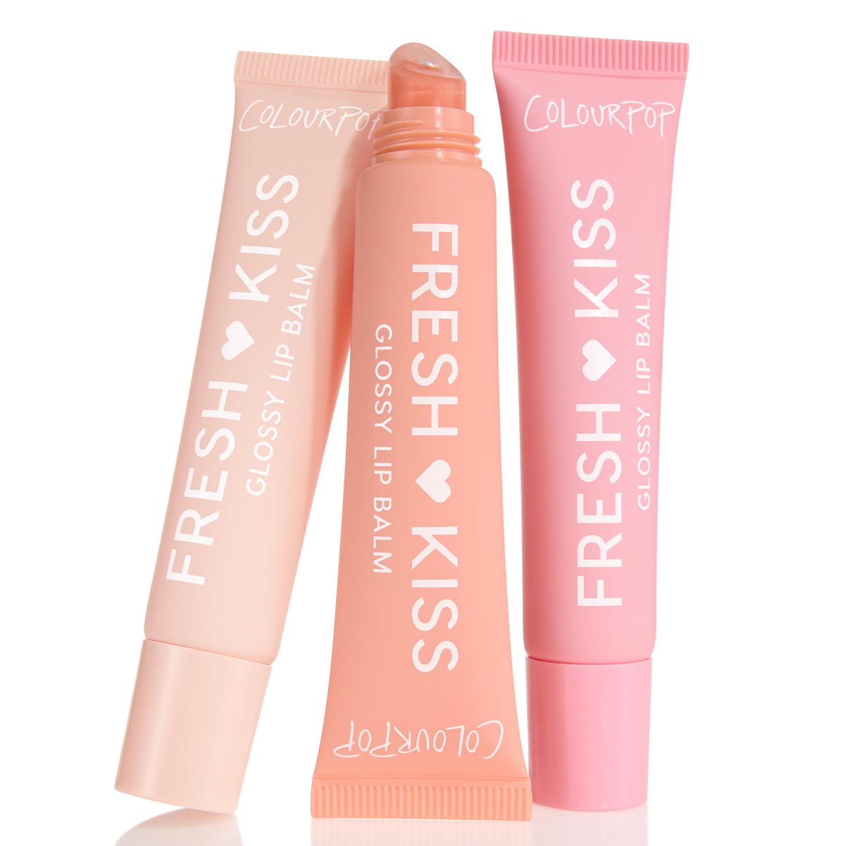 Pretty in Pastels ColourPop Glossy Lip Balm Trio showcases three Fresh Kiss glossy lip balms - soft pink, peach, and blush - with the center tube uncapped to show a slanted applicator, arranged upright on a white background.