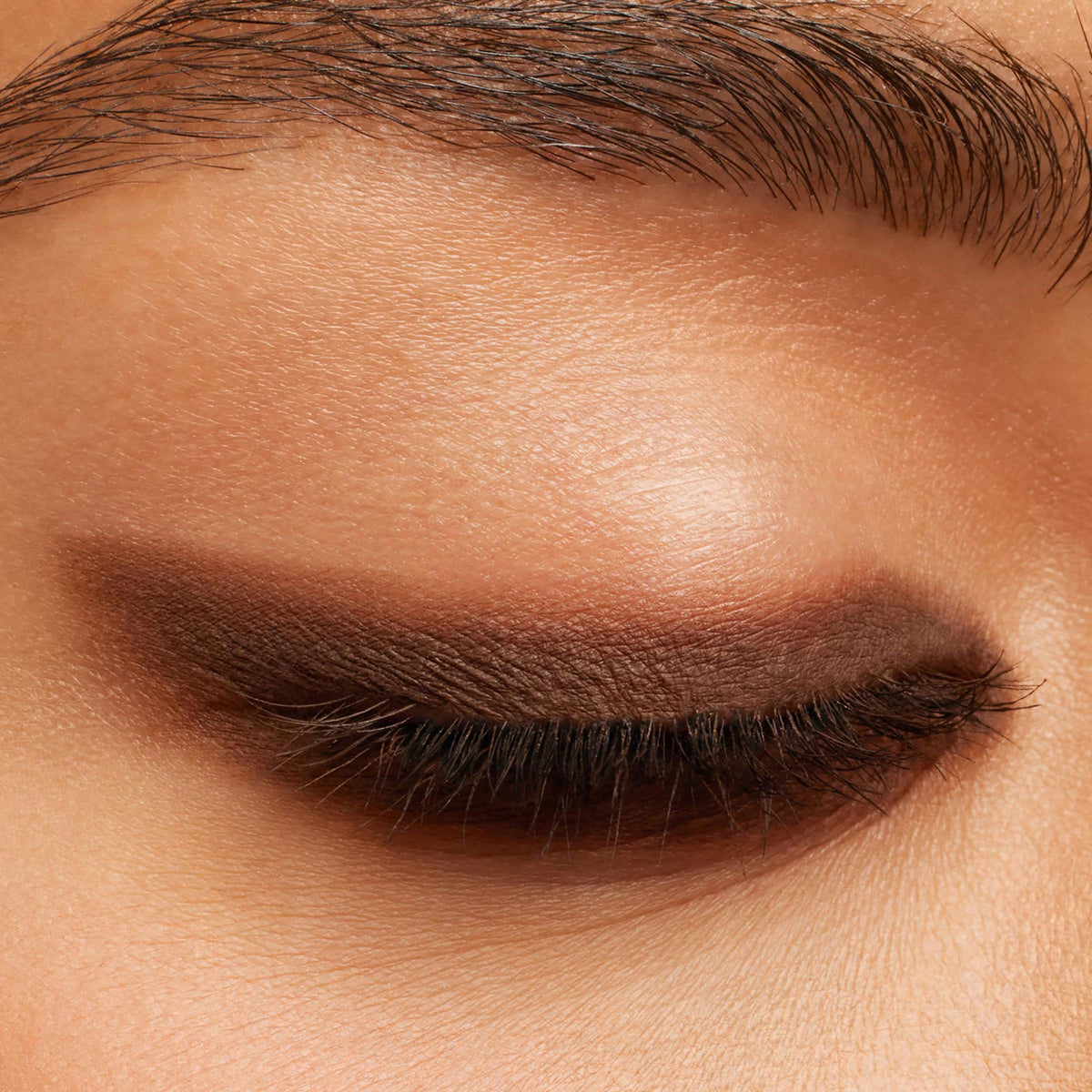 Closed eyelid showcases a soft, smoky wing in rich brown, applied with New BFF Crème Gel Liner for a smooth, matte finish; precise line hugs the lash line beneath a groomed brow, highlighting ColourPop Crème Gel Liner payoff and long-wear control.