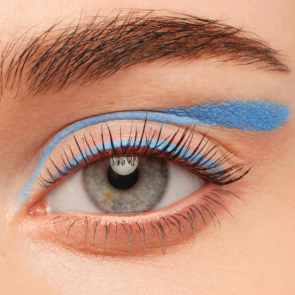 Out of the Blue ColourPop Crème Gel Liner sweeps a vivid cobalt line along the upper lashes and a thicker floating swipe above the crease, creating a bold graphic eye on a close-up lid with natural lashes and brow.