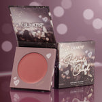 A-Lister cream blush compact sits open to reveal a warm rosy-mauve pan, with the matching box beside it; ColourPop Cream Blush Instant Crush packaging features heart doodles and sparkles against a mauve bokeh backdrop on a glossy surface.