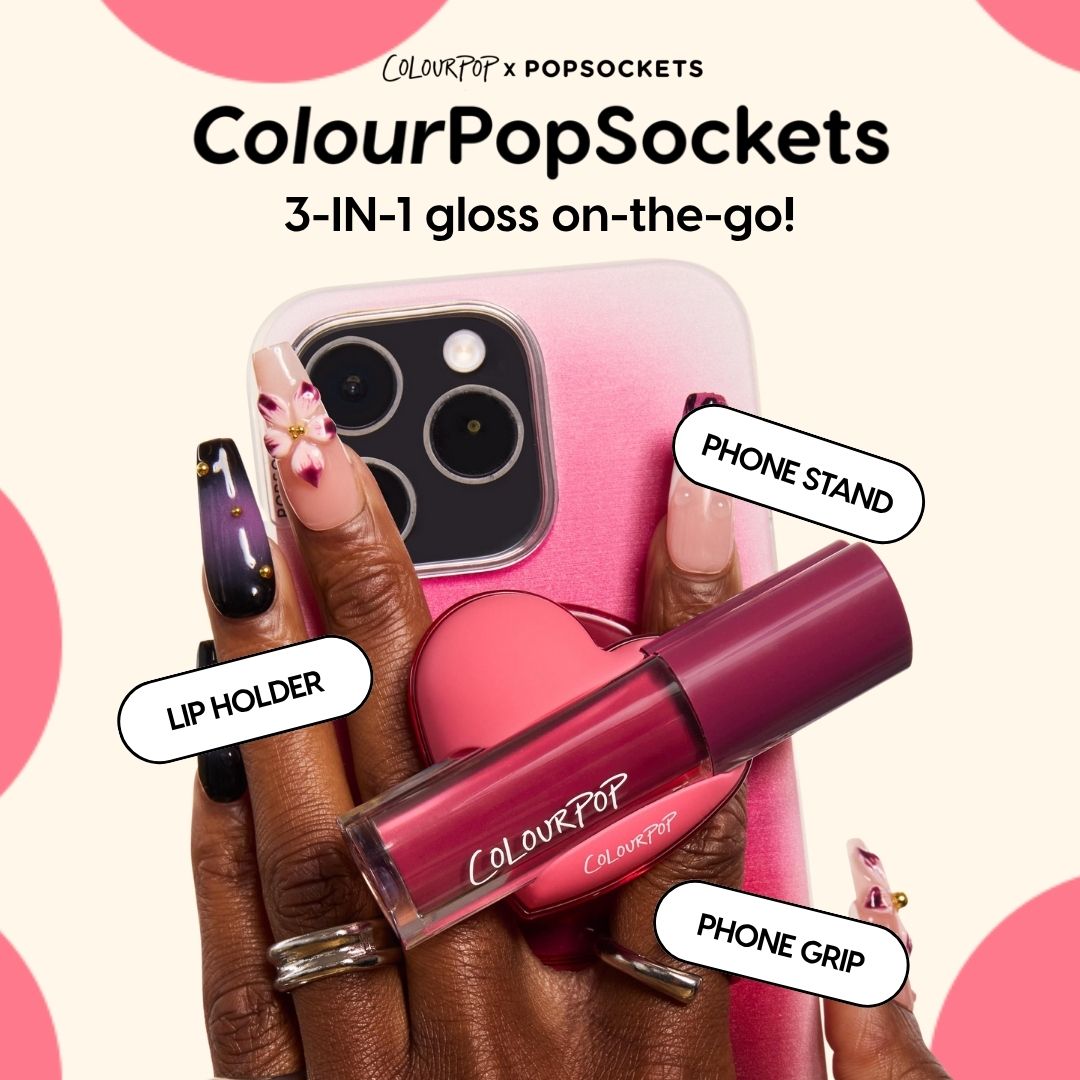 ColourPop Lip Stain tube snaps into a pink heart-shaped ColourPopSockets holder on a gradient pink smartphone, functioning as phone grip, stand, and lip holder while a hand with floral nail art grips the device - 3-in-1 on-the-go lip stain.