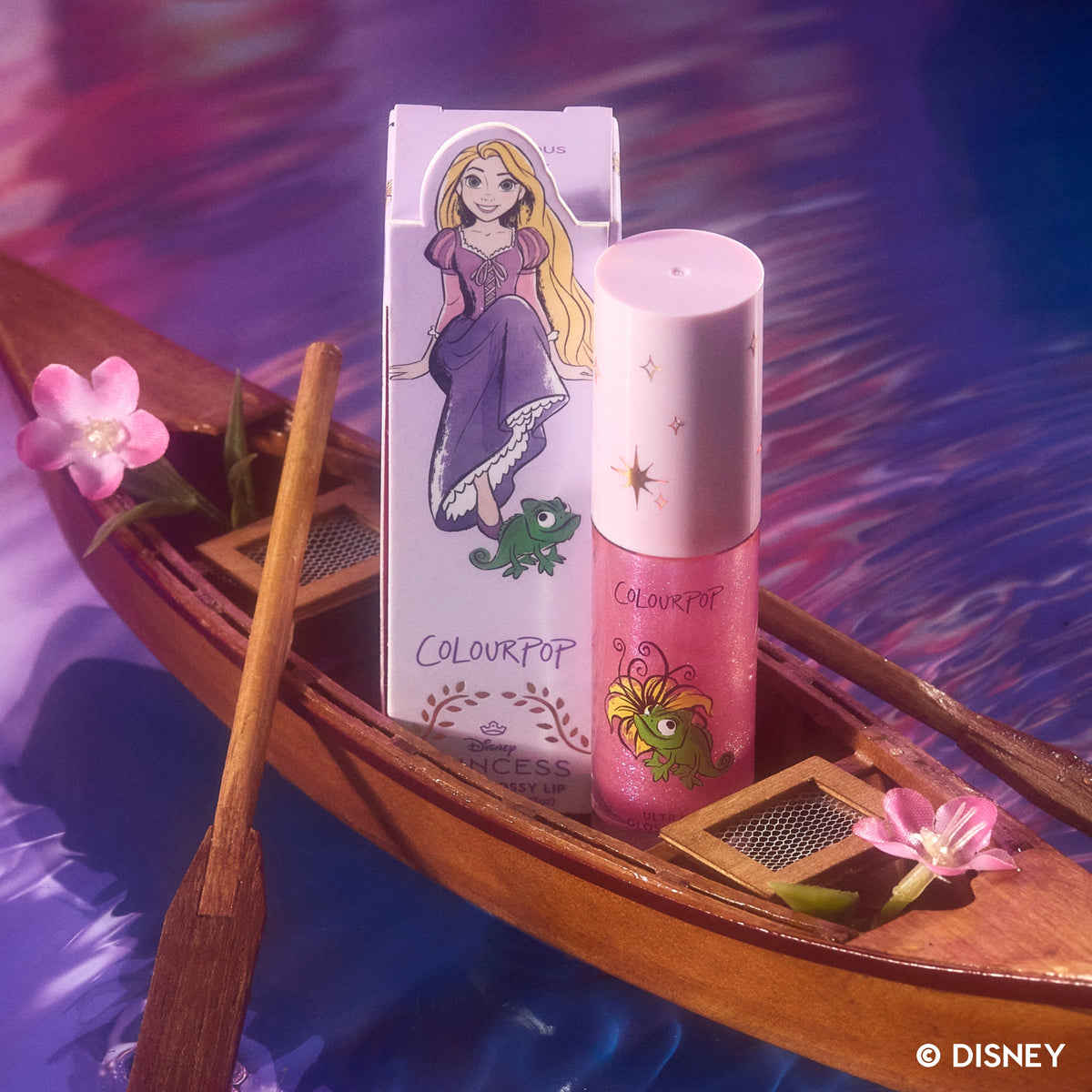ColourPop Courageous Rapunzel Ultra Glossy Lip from the Disney Princess collection standing beside its illustrated Rapunzel box on a wooden boat with pink flowers floating on shimmering purple water.