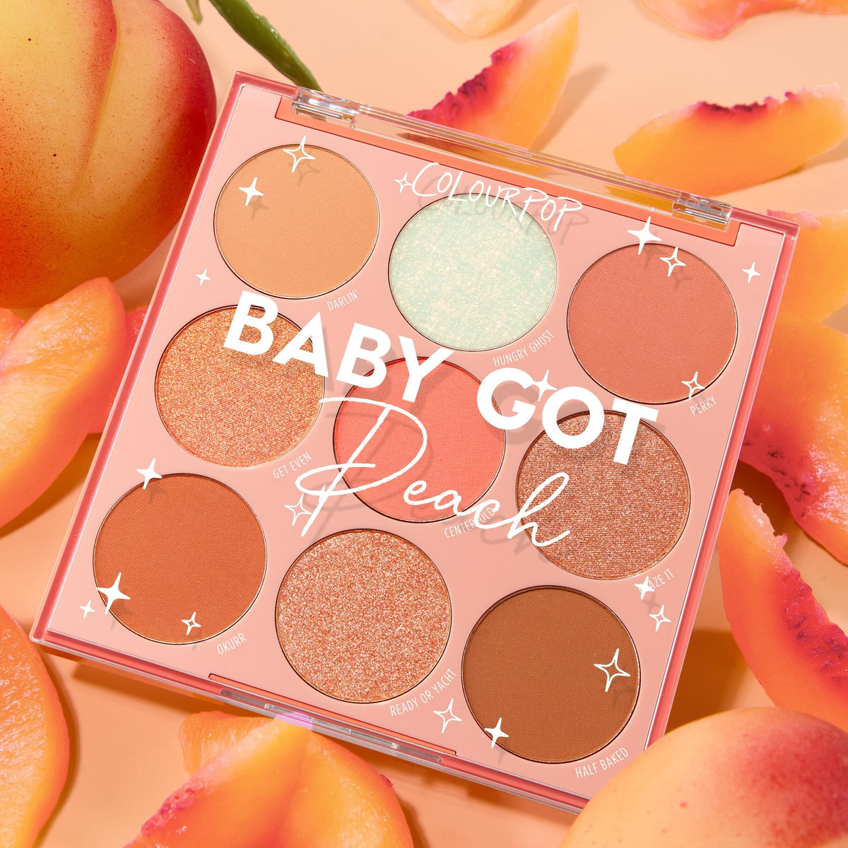 Baby Got Peach ColourPop Shadow Palette showcases nine peachy mattes and shimmers under a clear lid, the 9-pan arranged top-down and surrounded by ripe peach slices on a soft apricot backdrop.