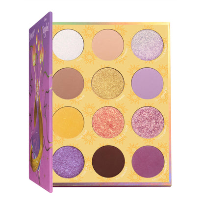 Best Day Ever ColourPop Shadow Palette half-open, revealing 12 shades - mattes and shimmers in white, beige, gold, yellow, lilac, purple, coral, and deep brown - in a sun-print tray, with a purple cover illustrated with Rapunzel and lanterns.