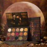 New Moon ColourPop Shadow Palette opens to 15 warm neutrals and vampy tones in matte and shimmer - gold, copper, berry, and olive - with Twilight: New Moon artwork of three characters under the lid, styled on forest rocks against a large moon backdrop.