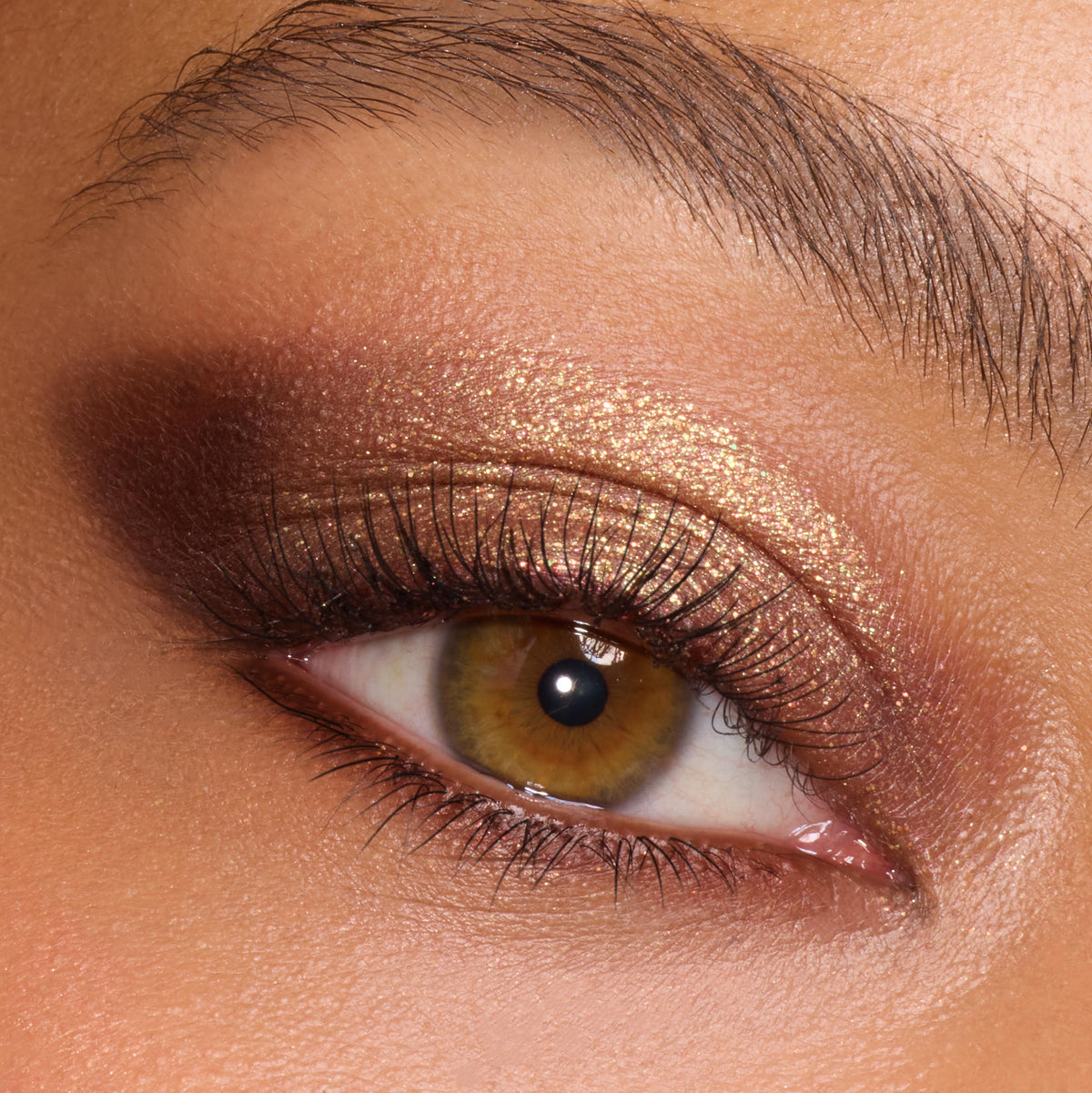 Bronze-gold metallic eyeshadow catches light on a close-up eye, blended into a deep brown smoky outer corner, showcasing the New Moon shadow palette, a ColourPop Shadow Palette, for warm neutral glam with defined lashes.