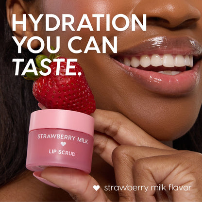 Strawberry Milk ColourPop Lip Scrub jar topped with a fresh strawberry, held beside glossy smiling lips; pink frosted pot reads “Strawberry Milk Lip Scrub,” highlighting the strawberry milk flavor in a close-up beauty product shot.