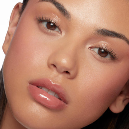 Glossy, peachy-pink lips wearing Hits Diff, ColourPop So Juicy Plumping Glossy Lip Oil, plumping to a smooth, glassy finish in a close-up beauty shot with dewy makeup and soft studio lighting.