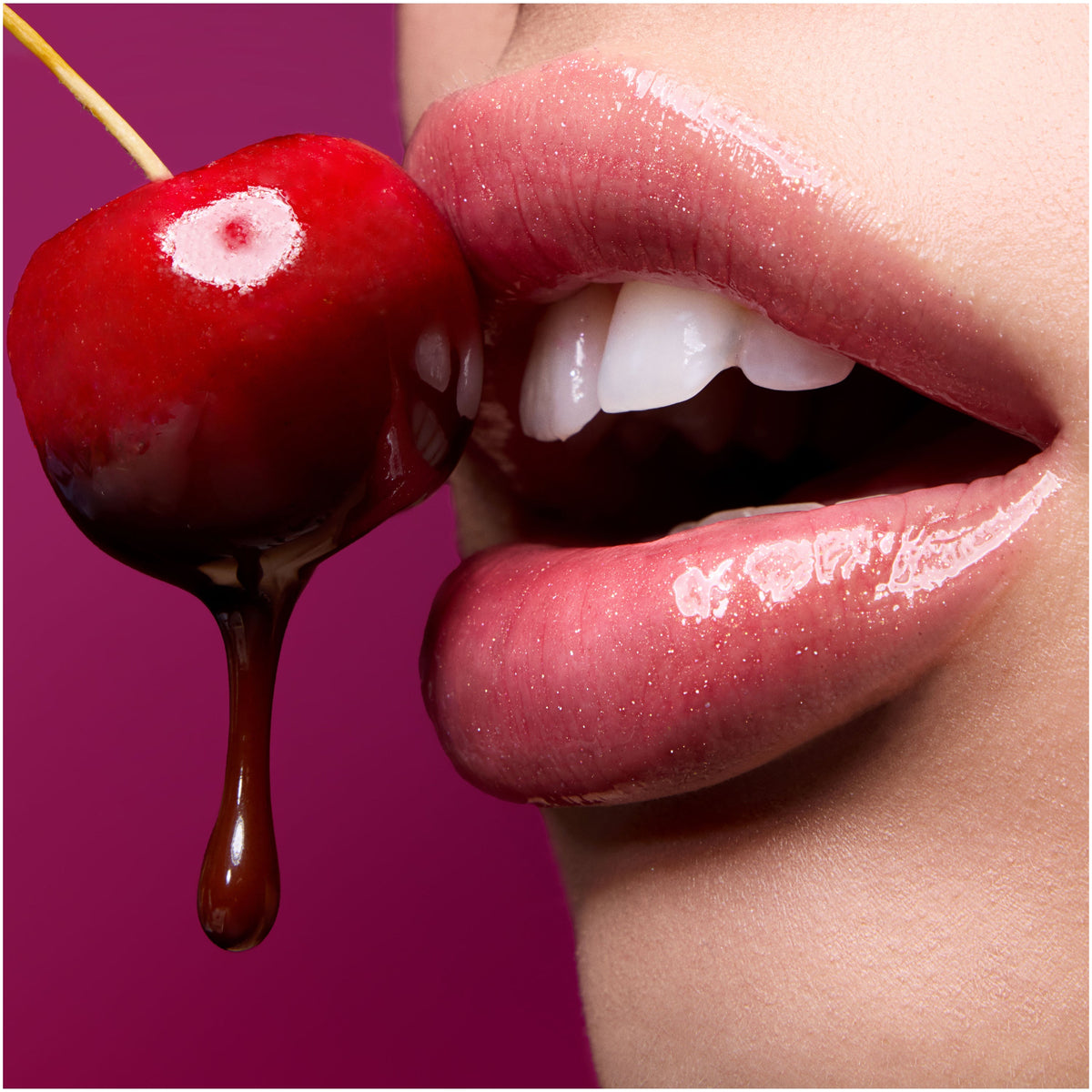 Close-up glossy pink lips wearing Colourpop Fresh Kiss Glossy Balm Chocolate Cherry shade parted near a chocolate-dipped red cherry against a deep red background, promoting luscious, juicy Lip Gloss & Lip Oil finish.