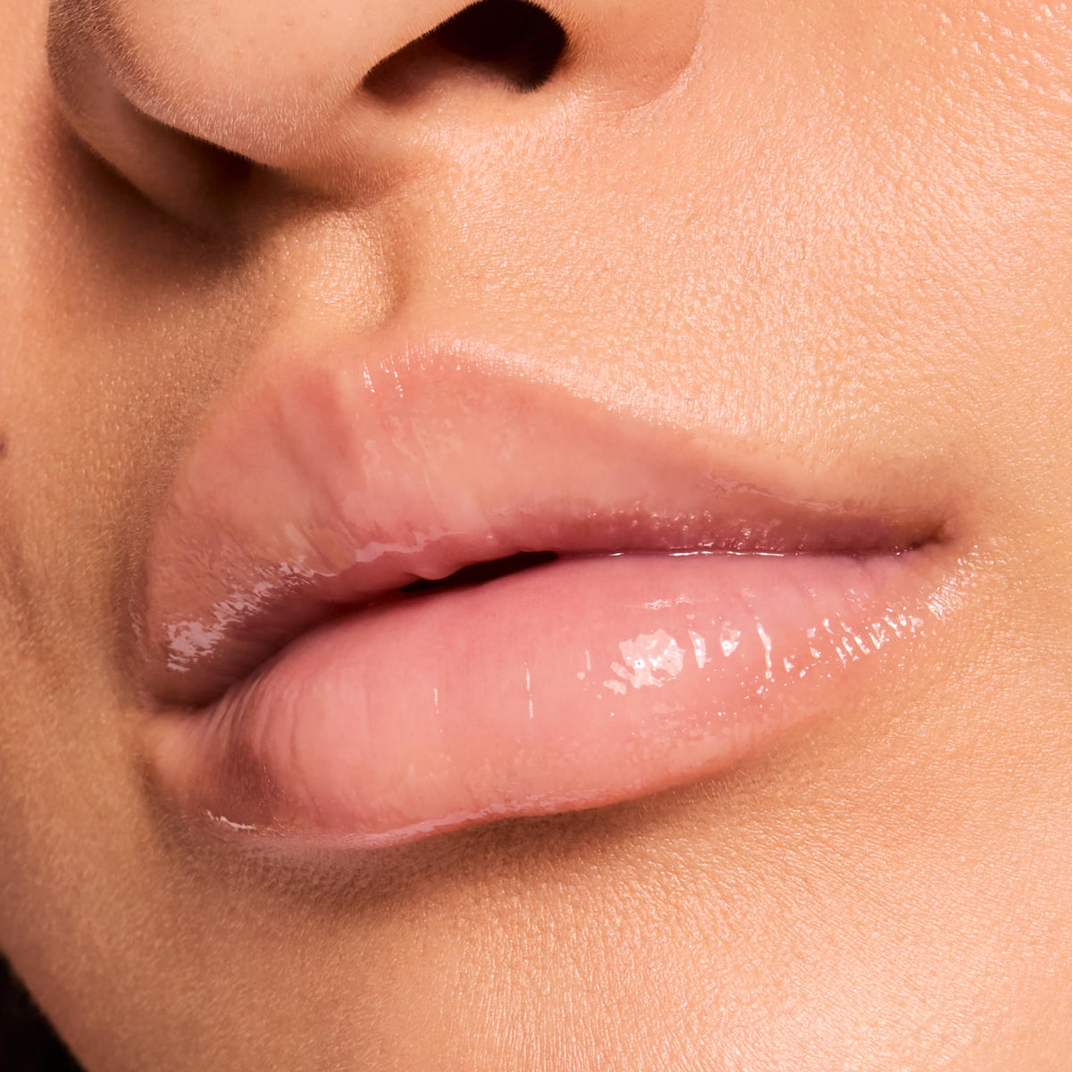 Glossy nude lips wearing ColourPop Fresh Kiss Glossy Balm in Vanilla Cake, captured in a tight macro close-up, showing a sheer pink-beige tint with high shine, smooth hydration, and a cushiony finish on natural skin.