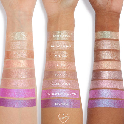 Three forearms with different skin tones display swatches of Colourpop Hallucinogenius Jelly Much Shadow eyeshadow shades, from champagne neutrals to vivid iridescent pinks and purples, showing shimmer payoff and color range.