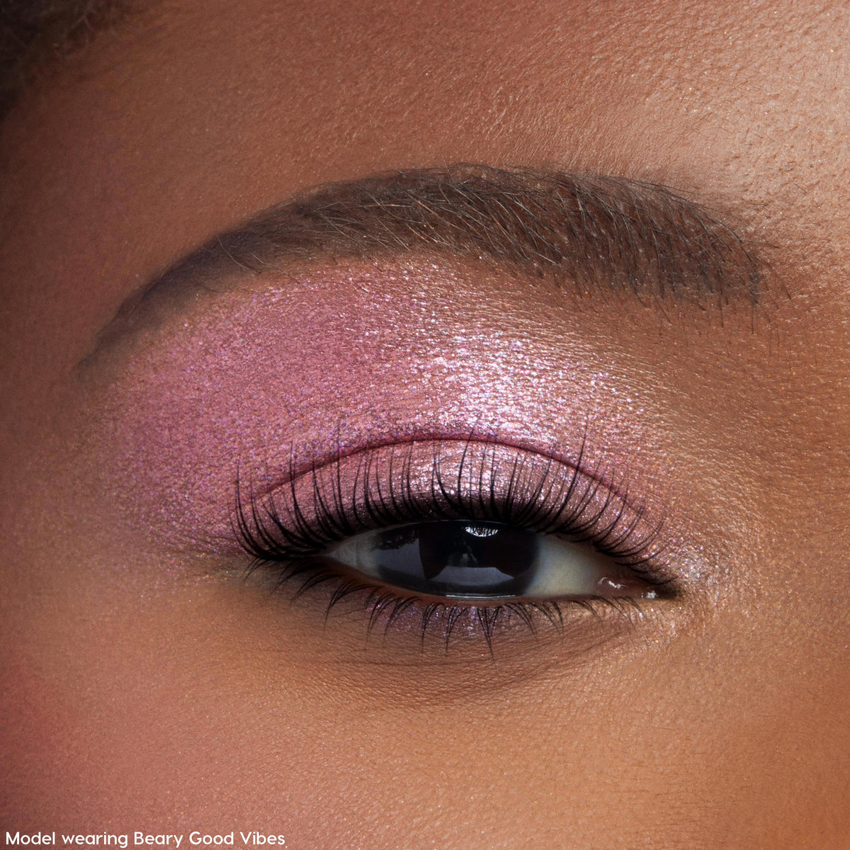 Shimmering pink‑lilac eyelid wearing Play All Day ColourPop Jelly Much Shadow, a metallic jelly eyeshadow swept across the lid with fine sparkle, framed by soft lashes and a groomed brow.