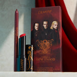ColourPop You Can't Trust Vampires Power Pout Lipstick stands uncapped to reveal a deep red bullet beside a plum lip pencil, set before a Twilight New Moon Volturi-themed box on a light stone surface with a red velvet backdrop.