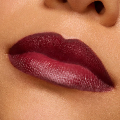 Lips wearing Slow Burn, a deep burgundy ColourPop Lux Lipstick, showing smooth full-coverage satin-matte color with crisp edges in a macro studio close-up, highlighting rich pigment and creamy texture.