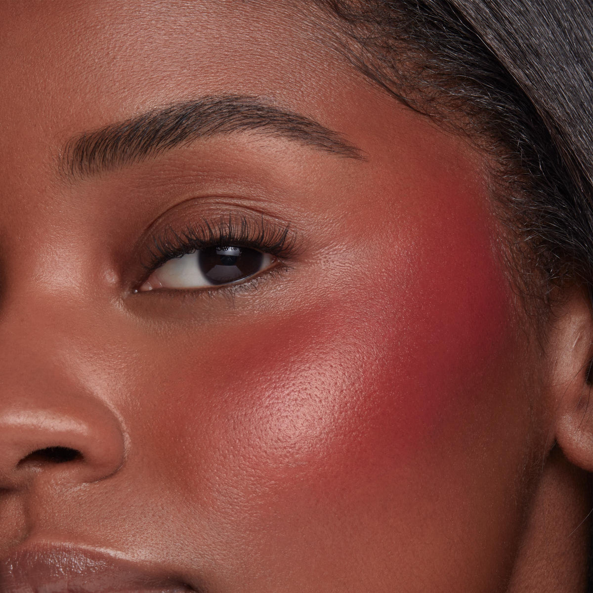 ColourPop Liquid Blush Royal Flush applied on a model’s cheek, rosy-red pigment blended from apple to temple with a dewy, luminous finish, close-up showcasing smooth, even payoff beside the eye.