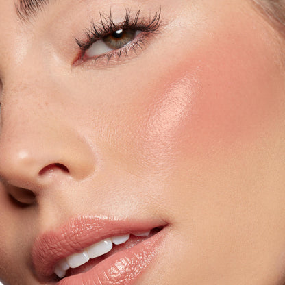 Larchmont Village Lip and Cheek Balm delivering a dewy peachy-pink flush on the cheek and a soft glossy nude tint on the lips, shown in a close-up beauty shot under natural light - ColourPop Lip and Cheek Balm with a skinlike glow.