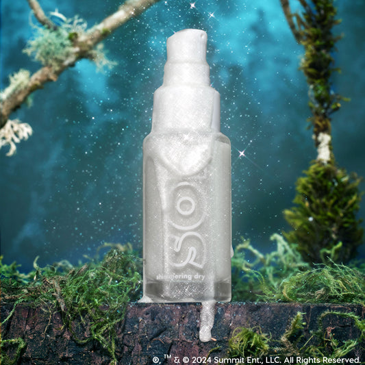 Like Diamonds SOL Shimmering Dry Oil frosted pump bottle glistens with icy silver shimmer and drips down the sides, standing on a mossy log against a starry teal forest; ColourPop SOL Shimmering Dry Oil for a luminous body glow.