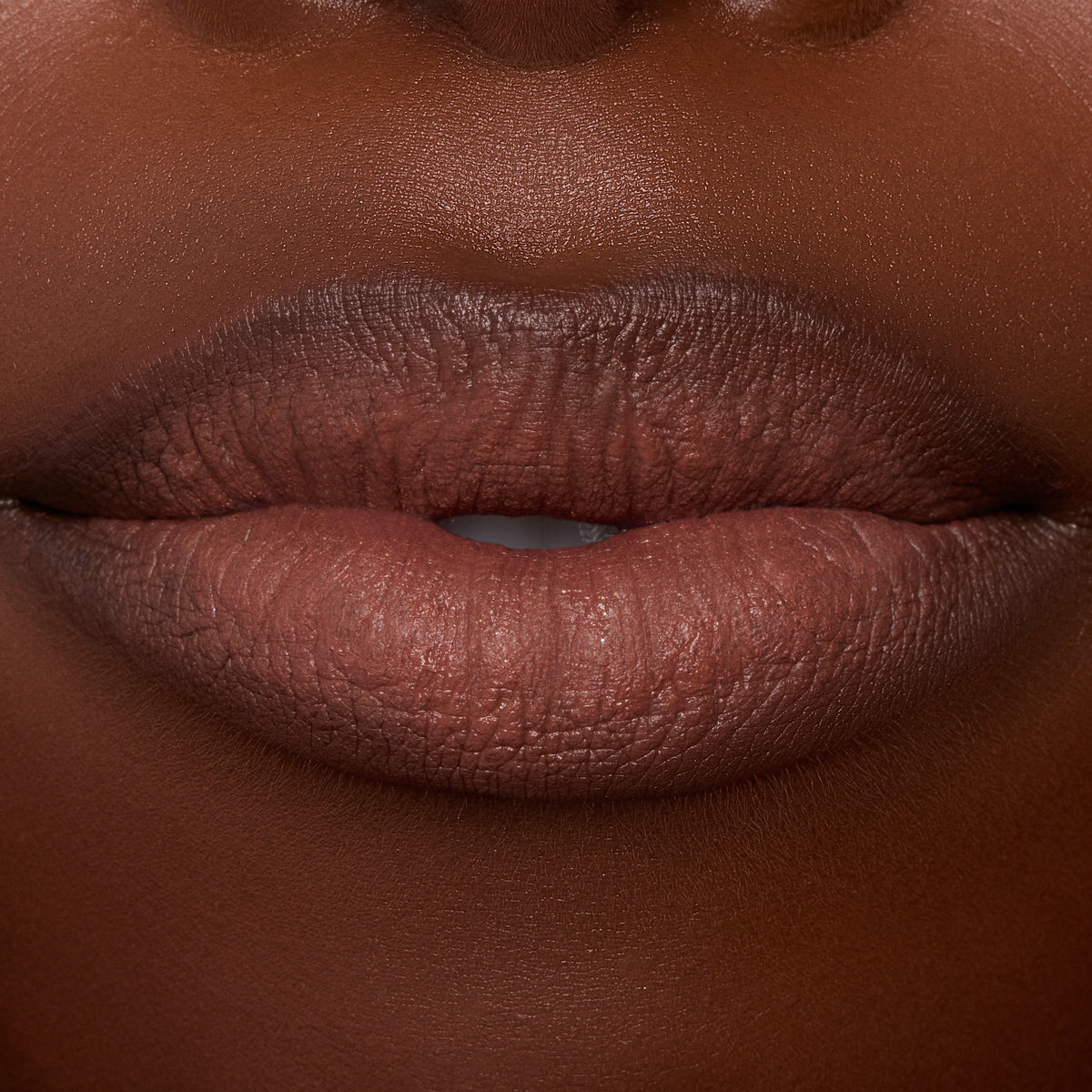 Lips wearing ColourPop Lippie Stix In the Nude, delivering creamy brown‑nude color with smooth, even coverage; macro studio close-up highlights hydrated texture and crisp lip line for an everyday lipstick look.