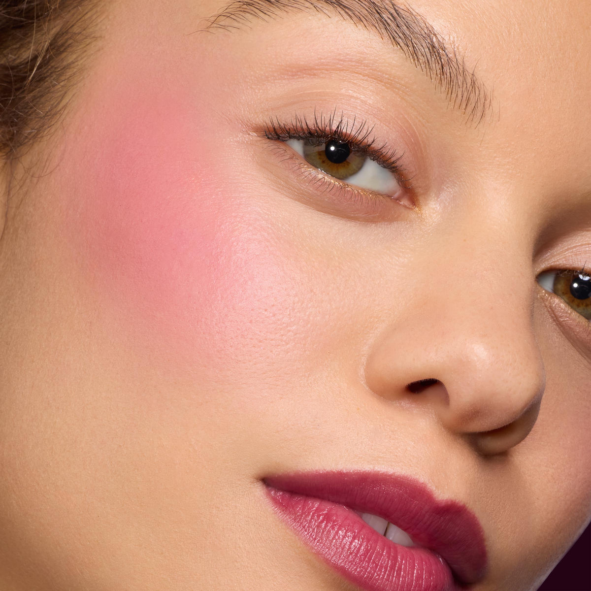 Ravished ColourPop Lip and Cheek Balm tinting lips a rich berry and cheeks a soft rosy pink, showing a dewy, blendable finish in a studio close-up with smooth skin texture, natural lashes, and a subtle glow.