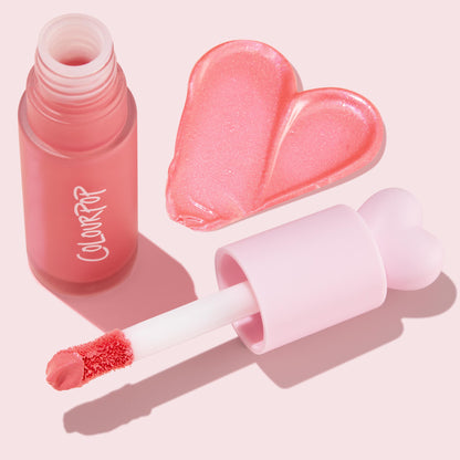 ColourPop Liquid Blush Princess Ave shown open with a frosted pink bottle and heart-topped wand, the doe-foot applicator loaded with shimmery pink pigment, next to a heart-shaped swatch on a light pink flat lay background.