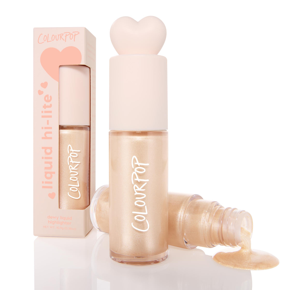 ColourPop Liquid Highlighter Sugar Donut bottle stands capped with a blush heart-shaped top, while an open vial pours dewy pearly champagne glow; a peach box labeled liquid hi-lite sits behind on a white studio background.