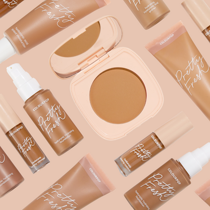 ColourPop Pretty Fresh Tinted Moisturizer in Medium Dark 14 W sits among matching Pretty Fresh foundation, concealer, and a powder compact in a nude flat lay, showcasing the hydrating hyaluronic acid formula and warm medium-dark coverage.