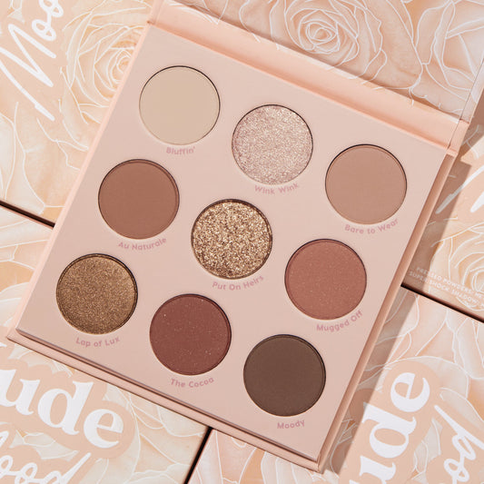 Nude Mood ColourPop Shadow Palette lying open, showcasing nine neutral pans - matte creams and browns plus shimmer and glitter shades like Wink Wink and Put On Heirs - arranged 3x3 in a blush case, set atop matching rose-print packaging.