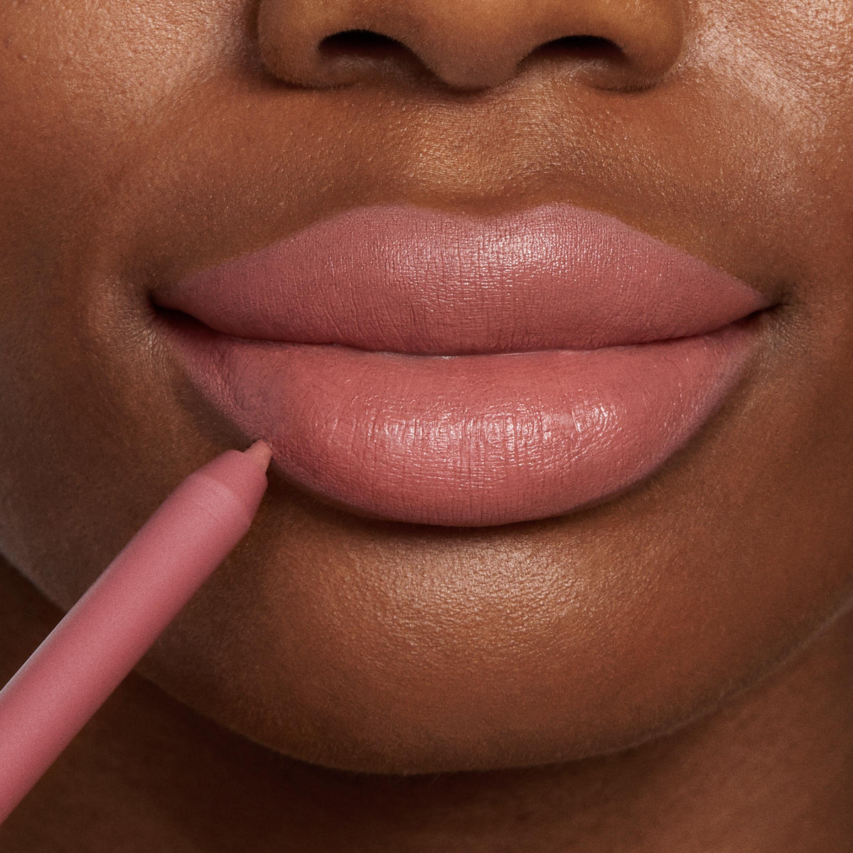 ColourPop Lippie Pencil Oh Snap lining full lips in a rosy nude, the creamy tip tracing the lower lip for a defined matte outline; close-up beauty shot on warm brown skin showcasing precise application of the lip liner.