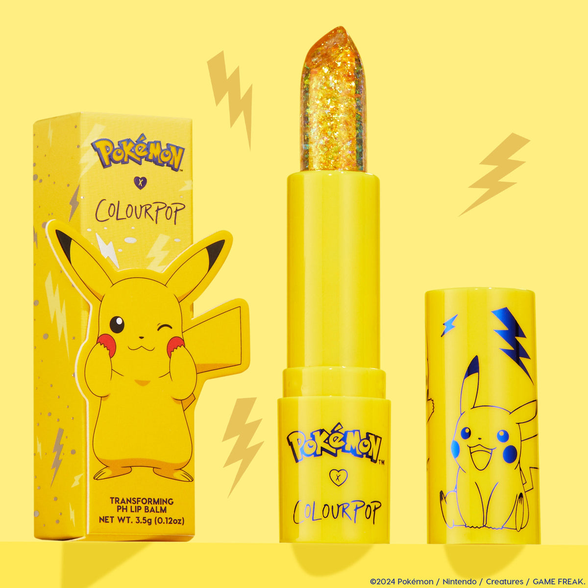 Thunderbolt transforming ColourPop pH Lip Balm bullet sparkles with gold flecks, standing uncapped between its Pikachu-printed yellow tube and matching box on a bright yellow backdrop with lightning accents, 3.5 g/0.12 oz.