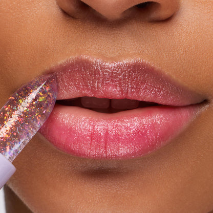 Transform ColourPop pH Lip Balm glides onto lips, a clear jelly balm with iridescent flakes in a lavender tube, reacting to pH to deliver a rosy pink, glossy finish; close-up beauty shot highlighting hydrated lips.