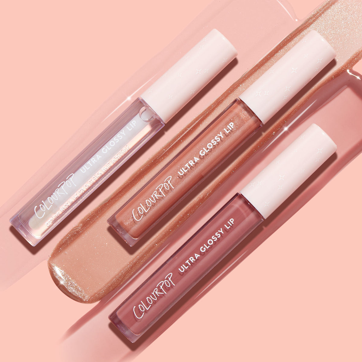 Three ColourPop Ultra Glossy Lip tubes - Perfect 4 U Ultra Glossy Lip bundle - rest diagonally on a peach backdrop, with glossy swatches showing clear sparkle, golden nude shimmer, and rosy pink finishes.